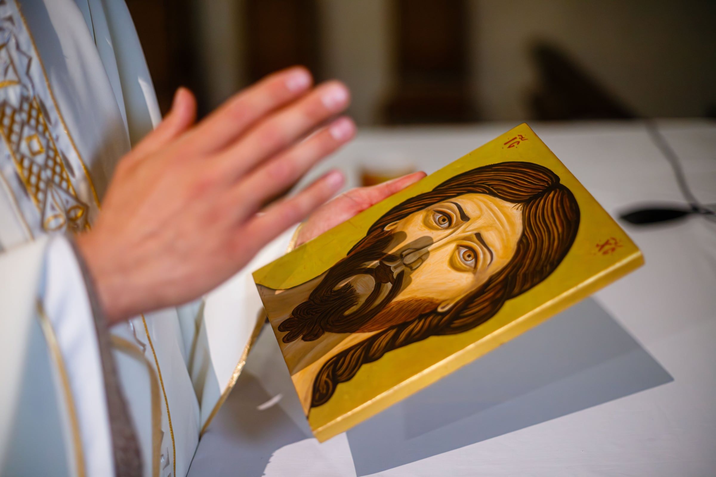 Les mains d'un prêtre bénissent une icône de la Sainte Face, posée sur l'autel
