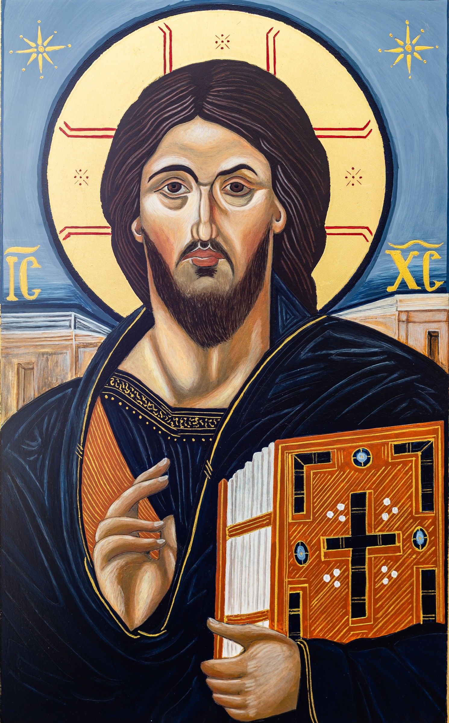 Icône du Christ Pantocrator en buste, bénissant de la main droite et tenant l'Évangile orné, nimbe crucifère doré, fond bleu étoilé avec architecture, inscriptions IC XC