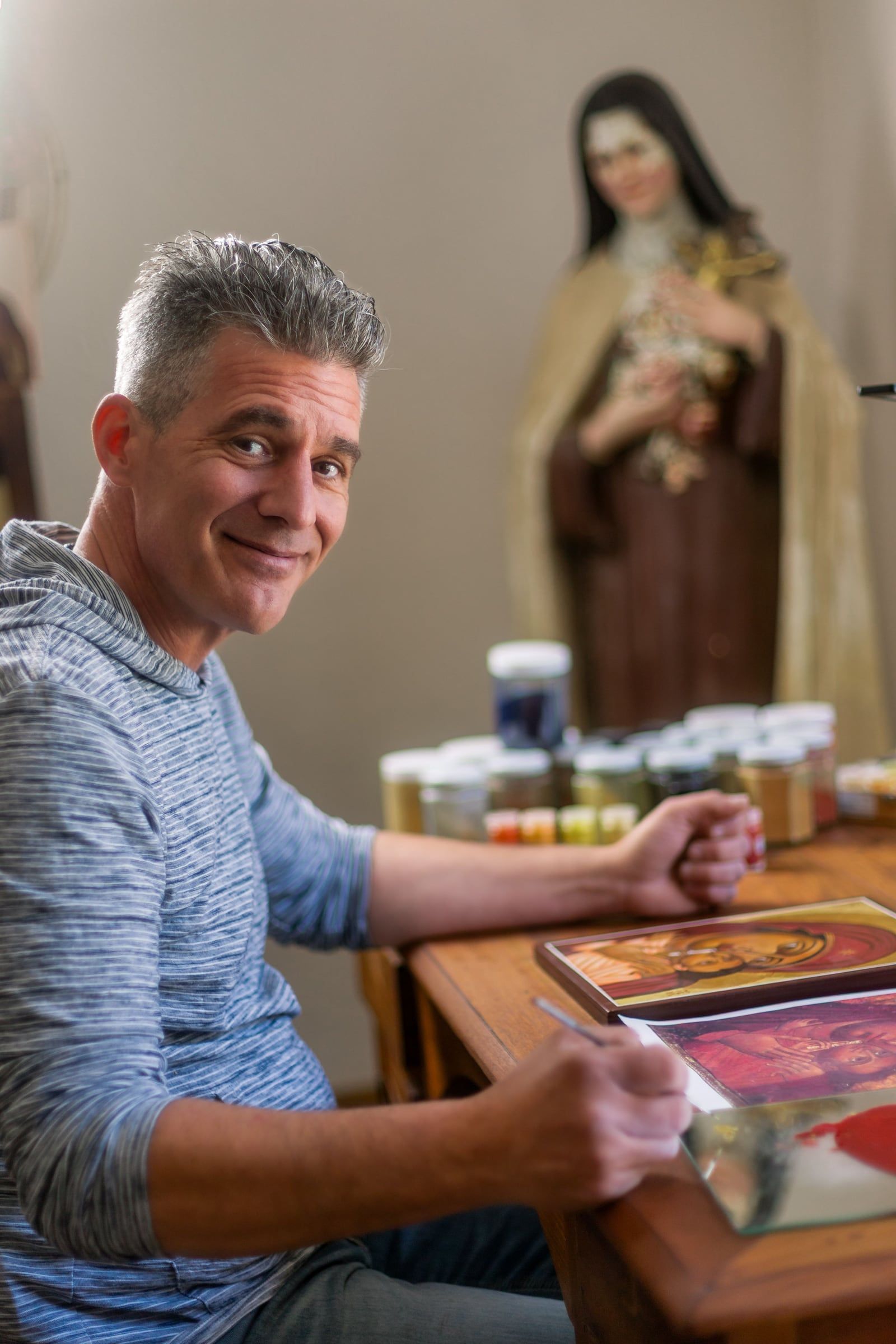 Fabien Tosello, iconographe, à sa table de travail, entouré de ses pinceaux et de ses pigments